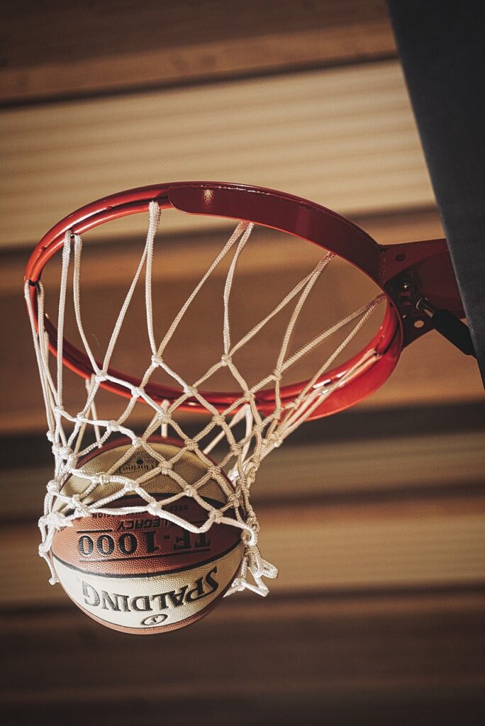 A close-up picture of a basketball passing through a basketball hoop