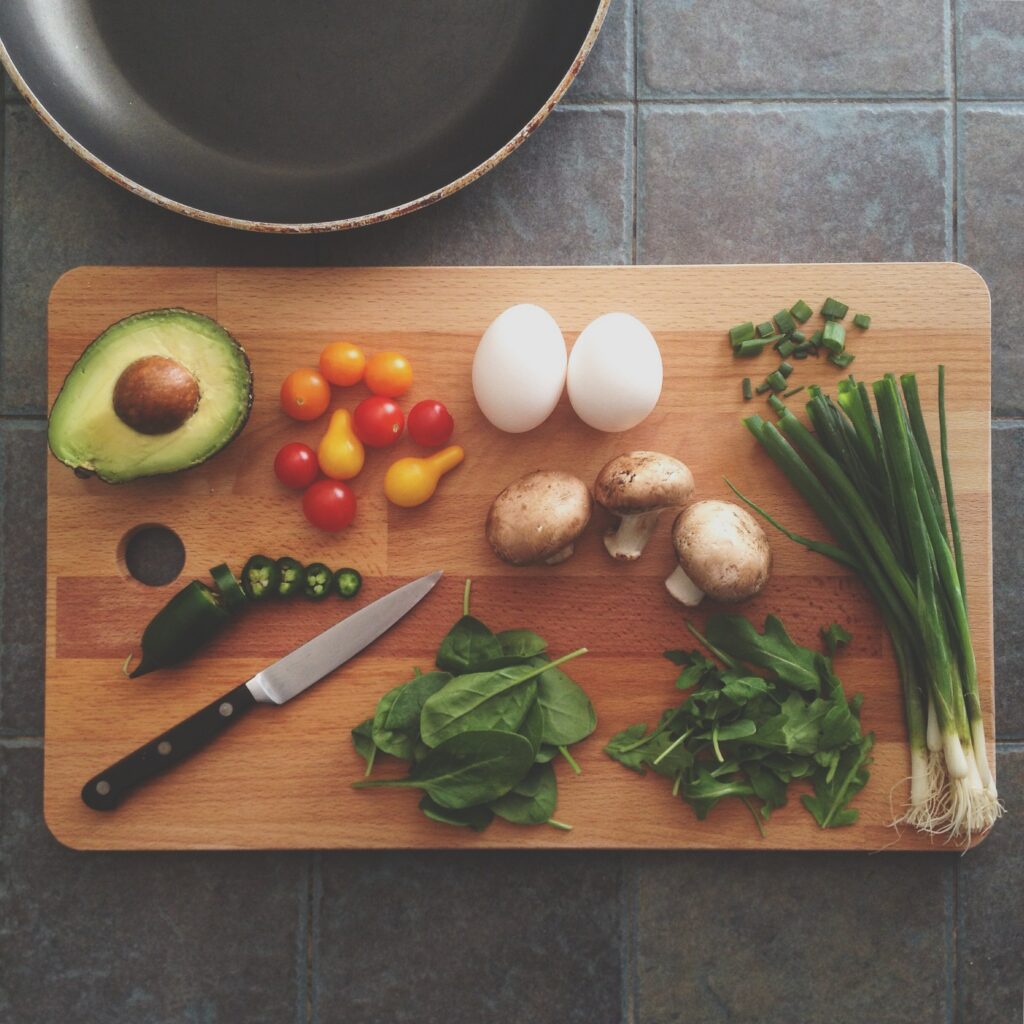 A variety of raw food and a knife put on a brown cutting board